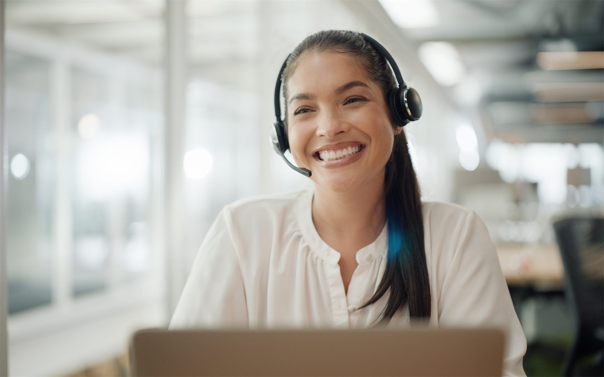 A virtual assistant wearing a headset working at a laptop
